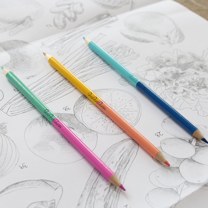 lot de trois crayons de couleur bicolore posés sur un coloriage avec illustrations détaillées de fruits et légumes - un citron, un céléri..-